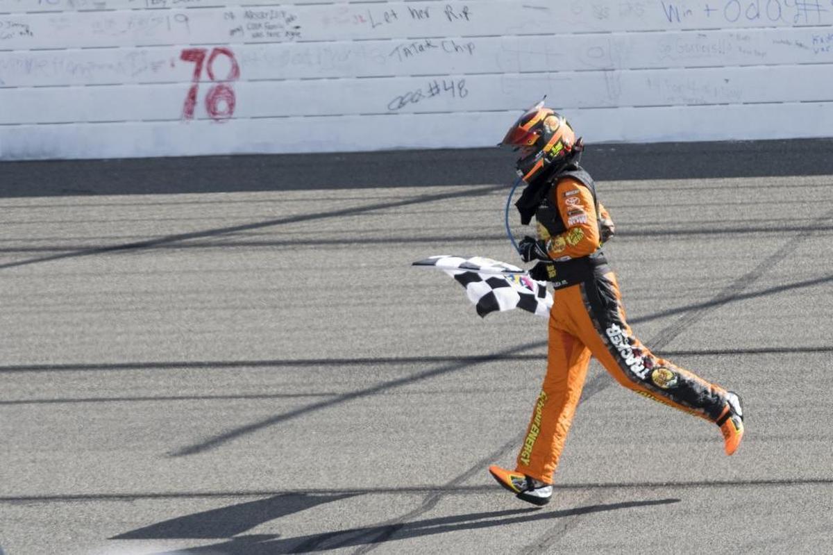 Defending NASCAR Cup Series champion Martin Truex Jr. runs with the checkered flag after winning Sunday’s Auto Club 400 race at Auto Club Speedway in Fontana, Calif.