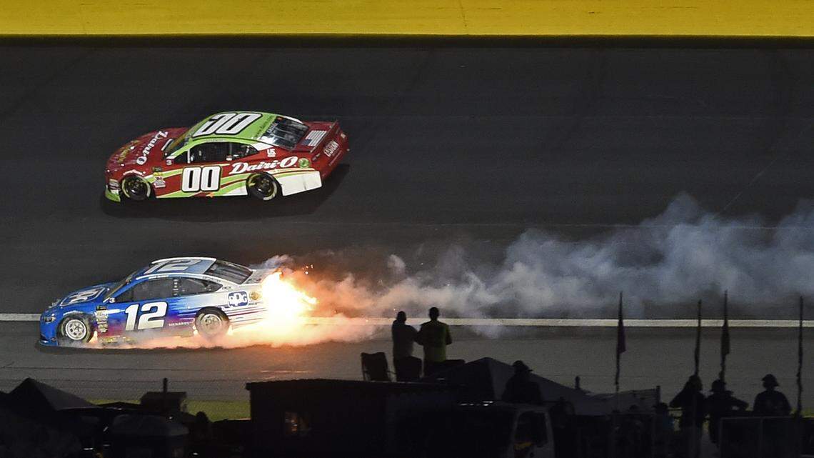 Fire erupts from the car of driver Ryan Blaney (12) as Landon Cassill (00) drives past during the NASCAR Cup Series auto race at Charlotte Motor Speedway in Charlotte, N.C., Sunday, May 27, 2018. (AP Photo/Mike McCarn)