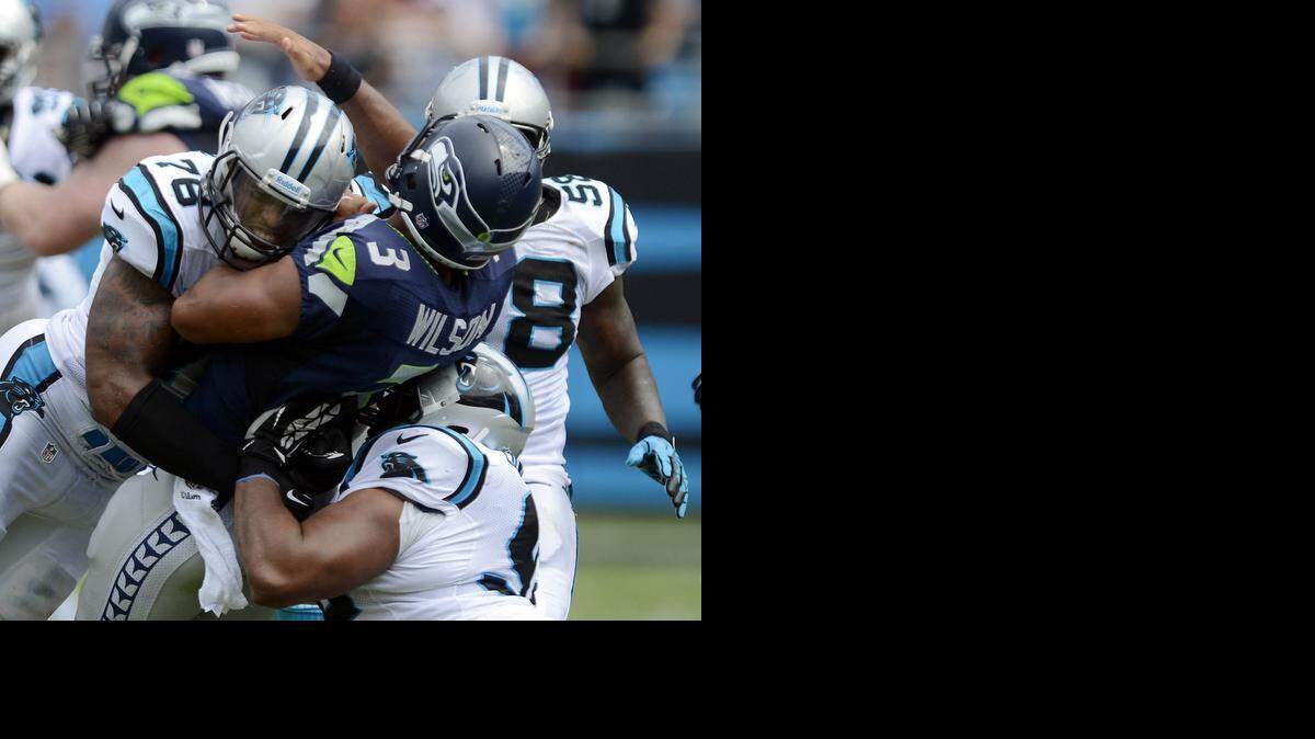 
Carolina Panthers Greg Hardy, left, and Dwan Edwards, lower right, sandwich the Seattle Seahawks’ Russell Wilson in the third quarter of their season-opening game at Bank of America in 2013. Edwards said Wednesday he likes Hardy but understands the team’s decision not to bring him back. 
