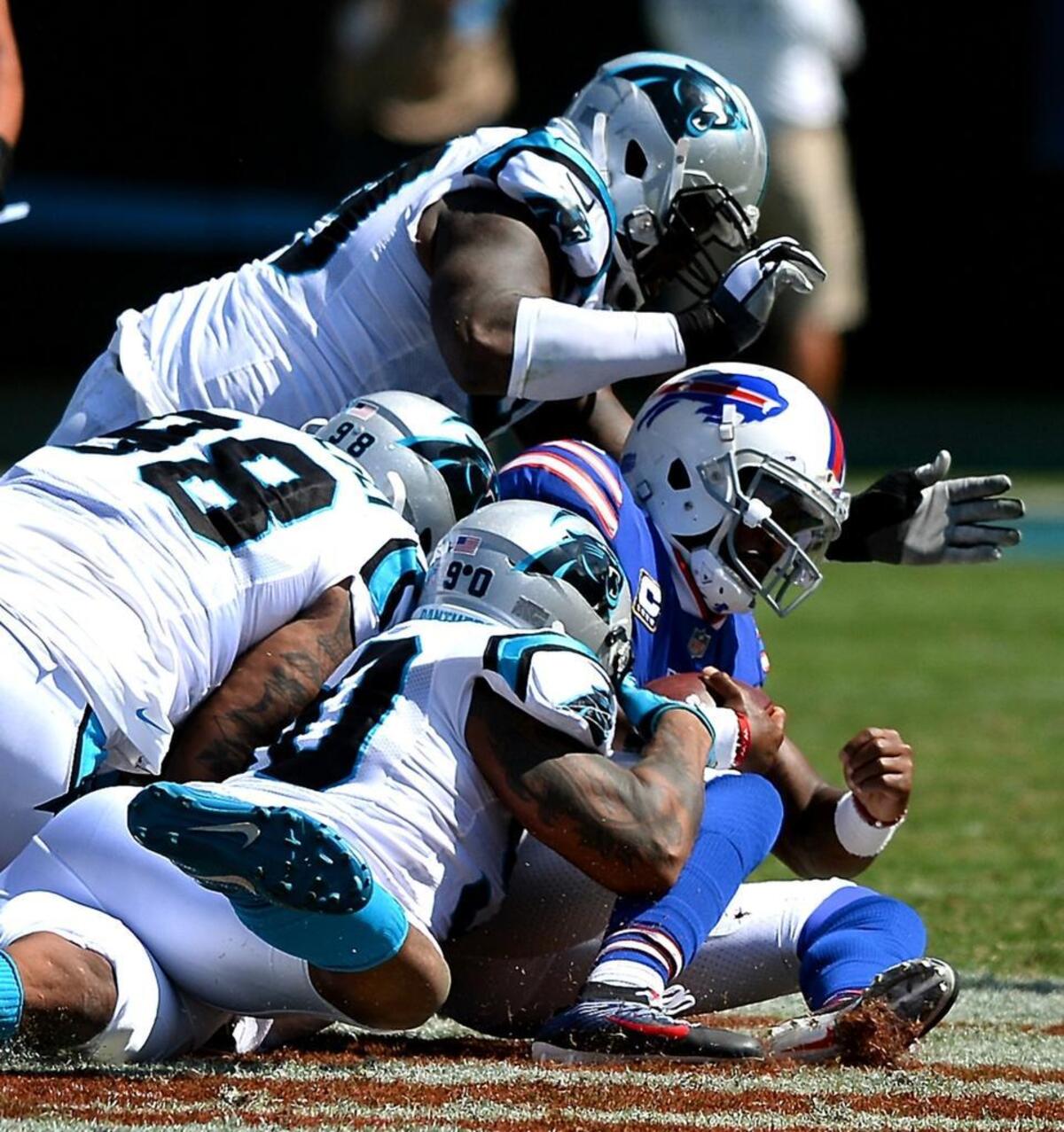 The Carolina Panthers defense, including defensive end Julius Peppers (90) and defensive tackle Star Lotulelei (98), pile onto Buffalo quarterback Tyrod Taylor in the third quarter Sunday of Carolina’s 9-3 win.