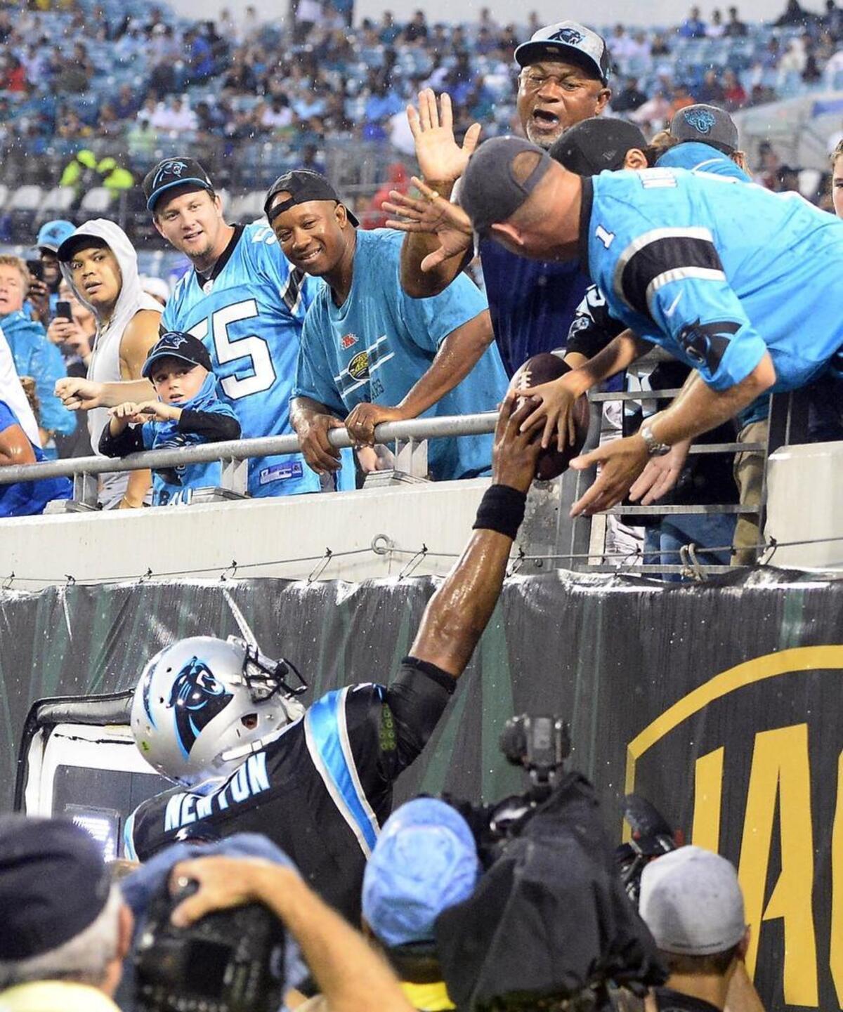 Carolina Panthers quarterback Cam Newton hands a young fan a football after throwing a touchdown pass against the Jacksonville Jaguars in Thursday night’s preseason game. Newton saw his first live action since January.