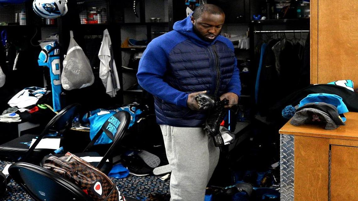 Carolina Panthers defensive end Charles Johnson looks at a pair of his cleats as he cleans out his locker at Bank of America Stadium on Jan. 2. Johnson will be back for two years after re-signing on Tuesday.