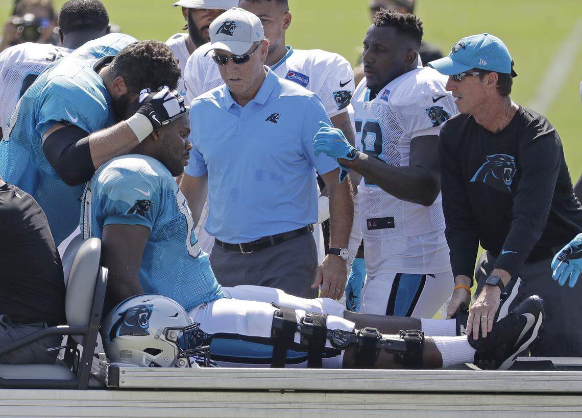 Carolina Panthers’ Daryl Williams, center, is comforted by Matt Kalil, left, after getting injured during NFL football practice at the team’s training camp in Spartanburg, S.C., Saturday, July 28, 2018. (AP Photo/Chuck Burton)
