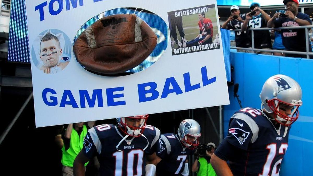 
New England Patriots quarterback Tom Brady, right, runs past Larry Smith's sign on Friday at Bank of America Stadium in Charlotte. The Carolina Panthers hosted the Patriots in preseason action. Smith is from Newland.
