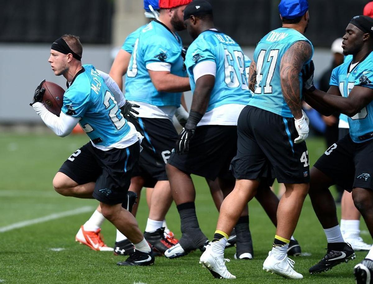 Carolina Panthers rookie running back Christian McCaffrey, left, breaks free of the pack on a handoff in a minicamp practice.