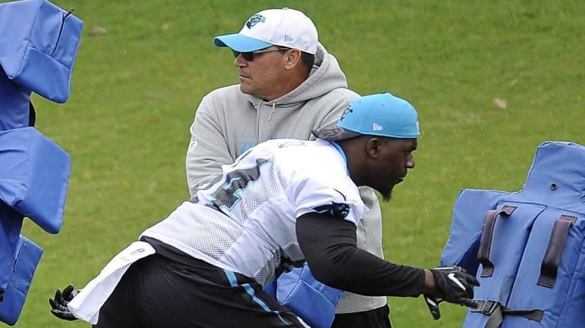 Carolina Panthers head coach Ron Rivera watches as Bryan Cox Jr. (64) runs through the tackling sleds during the first session of the team’s rookie camp on May 5.