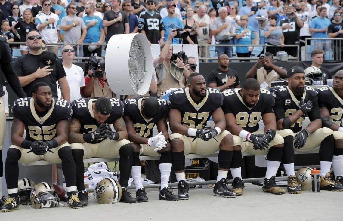 New Orleans Saints players sit on the bench during the national anthem before Sunday’s game against the Carolina Panthers at Bank of America Stadium in Charlotte.