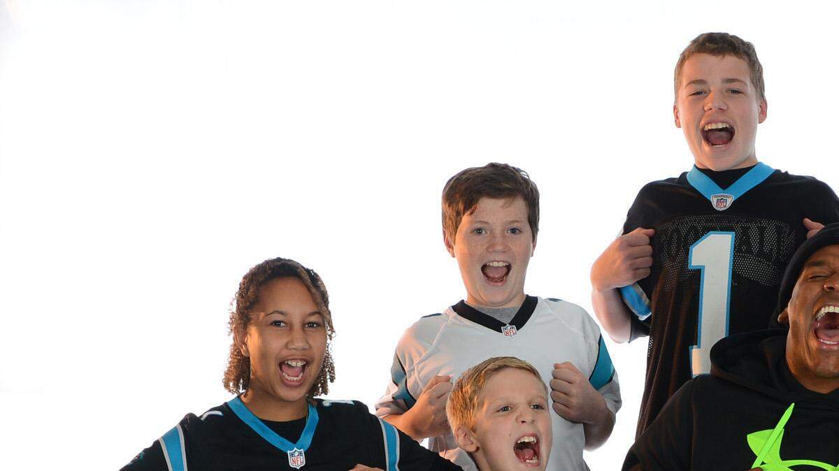 Carolina Panthers (1) quarterback Cam Newton strikes his "Superman" pose with a group of children all of whom have received a football from him following a Panthers touchdown. 