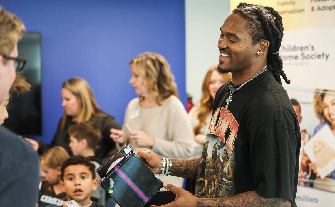 Panthers running back Rico Dowdle smiles as he signs footballs for kids at Children’s Home Society of North Carolina (CHS) in Charlotte, NC on Friday, November 14, 2025. Dowdle presented CHS with a check for $45,000 as a he turned a penalty into purpose, transforming a fine for his touchdown celebration into a charitable cause.