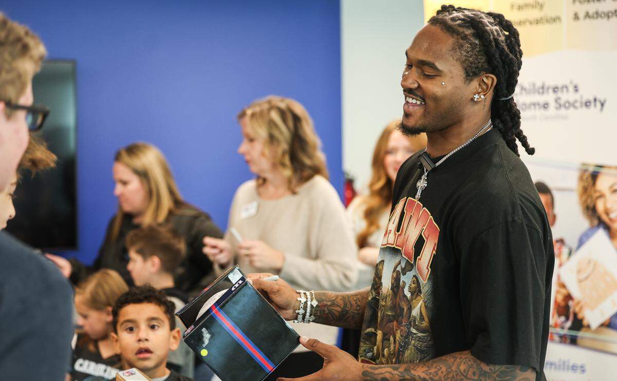 Panthers running back Rico Dowdle smiles as he signs footballs for kids at Children’s Home Society of North Carolina (CHS) in Charlotte, NC on Friday, November 14, 2025. Dowdle presented CHS with a check for $45,000 as a he turned a penalty into purpose, transforming a fine for his touchdown celebration into a charitable cause.
