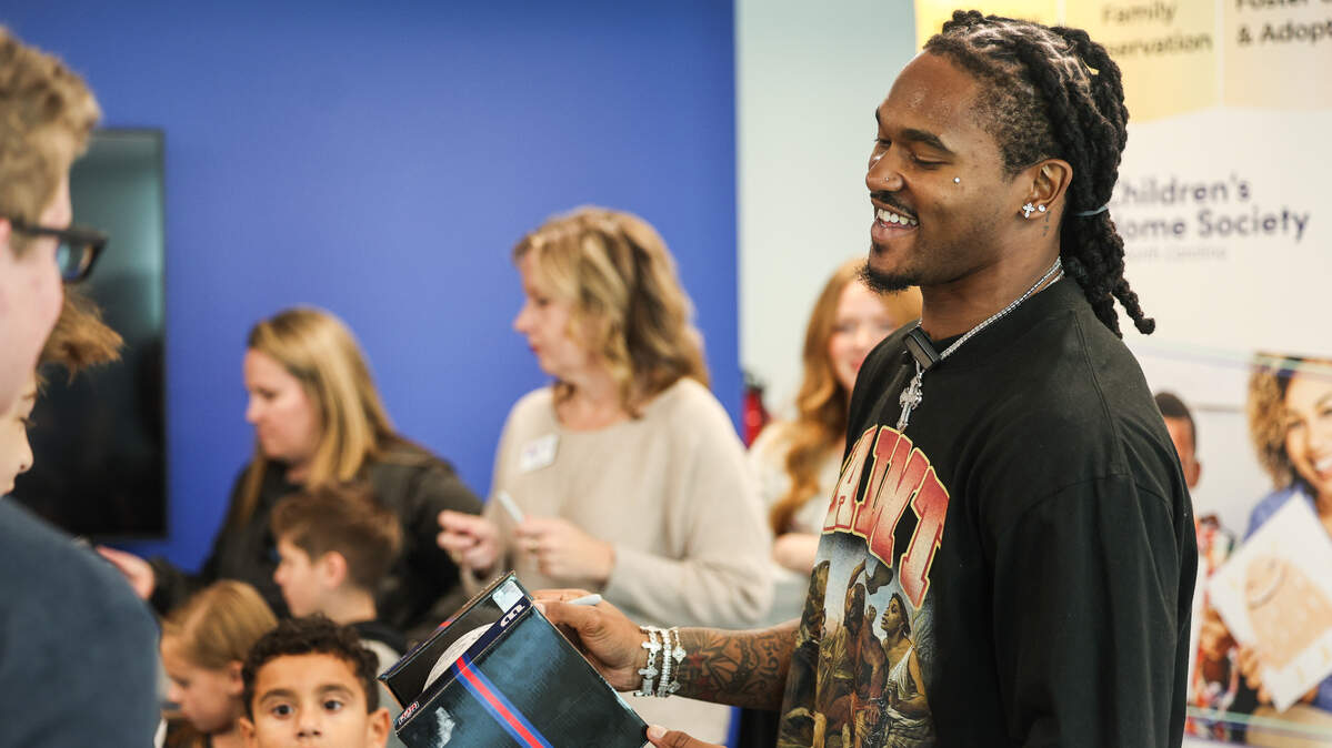 Panthers running back Rico Dowdle smiles as he signs footballs for kids at Children’s Home Society of North Carolina (CHS) in Charlotte, NC on Friday, November 14, 2025. Dowdle presented CHS with a check for $45,000 as a he turned a penalty into purpose, transforming a fine for his touchdown celebration into a charitable cause. 