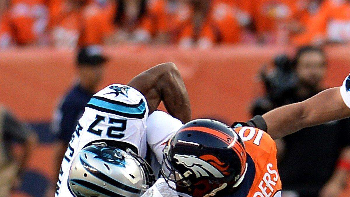 Carolina Panthers cornerback Robert McClain upends Denver Broncos wide receiver Emmanuel Sanders after a pass reception as Panthers linebacker Luke Kuechly, right, looks to assist on the play during first-quarter action at Sports Authority Field at Mile High in Denver on Thursday night.