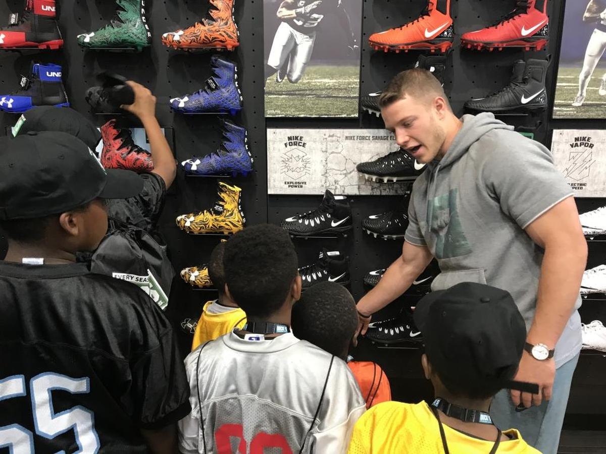 Carolina Panthers running back Christian McCaffrey helps youth football players pick out pairs of cleats during a shopping spree at SouthPark Mall on Friday.