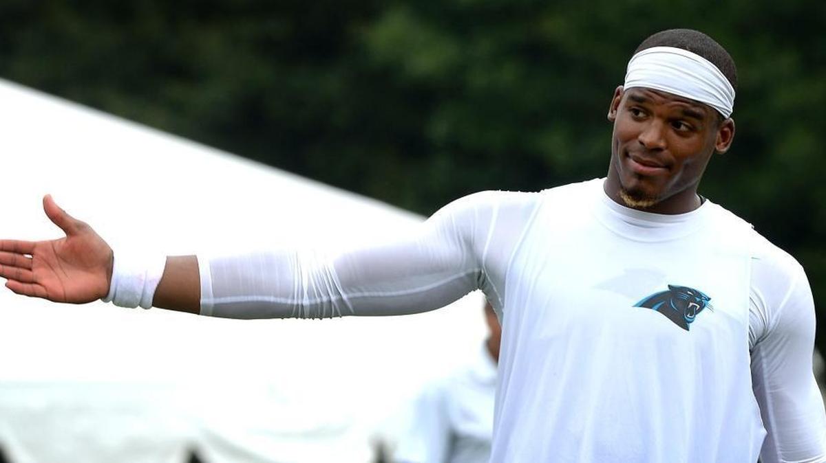 Carolina Panthers quarterback Cam Newton motions fans seeking autographs to move up the hill as he walks across a practice field following Wednesday’s practice in Spartanburg.