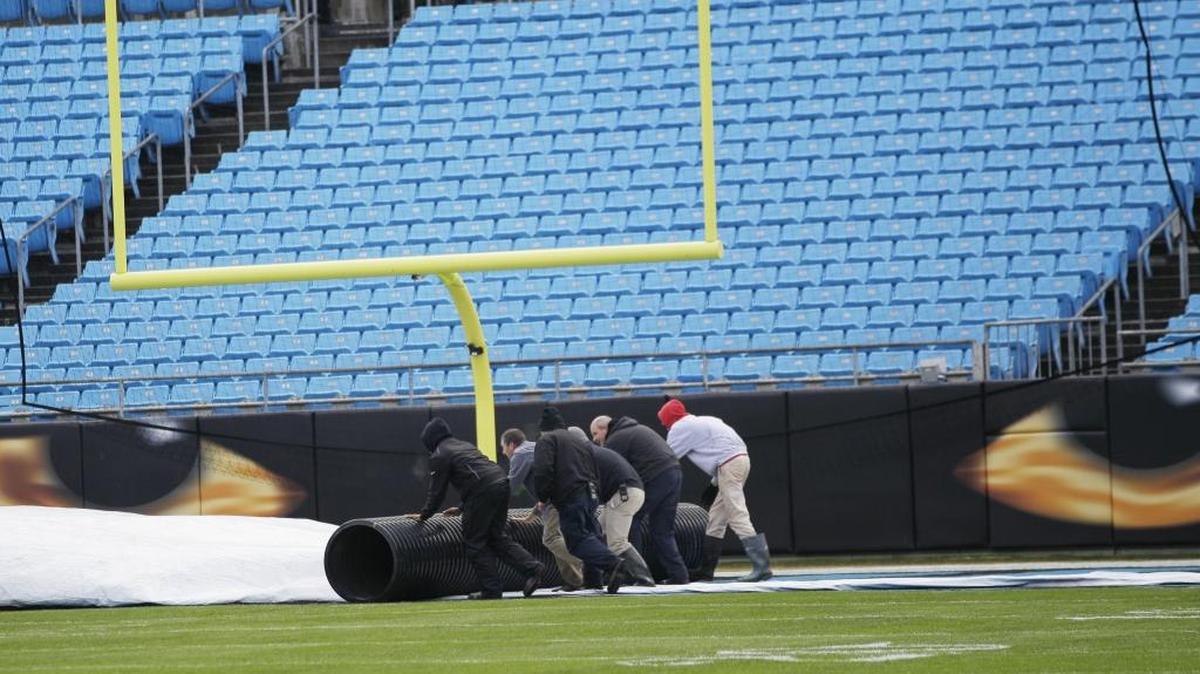 A grounds crew removes a tarp over the turf at Bank of America stadium before the first half of an NFL divisional playoff football game between the Carolina Panthers and the Seattle Seahawks, Sunday, Jan. 17, 2016, in Charlotte.