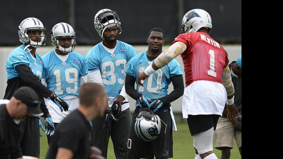 
Carolina Panthers quarterback Cam Newton, right, runs over to slap hands with wide receivers before beginning drills during practice on June 4, 2015.
