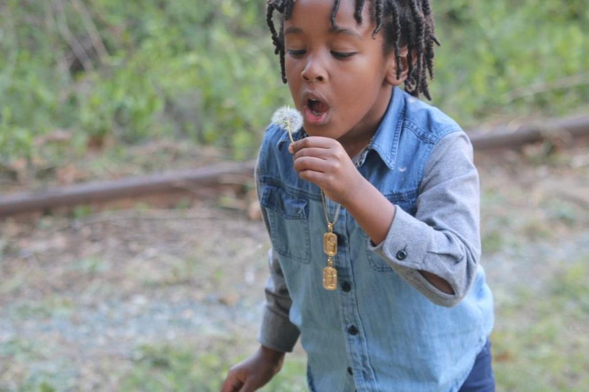 Prince Johnson, son of Panthers defensive end Charles Johnson, blows on a dandelion.