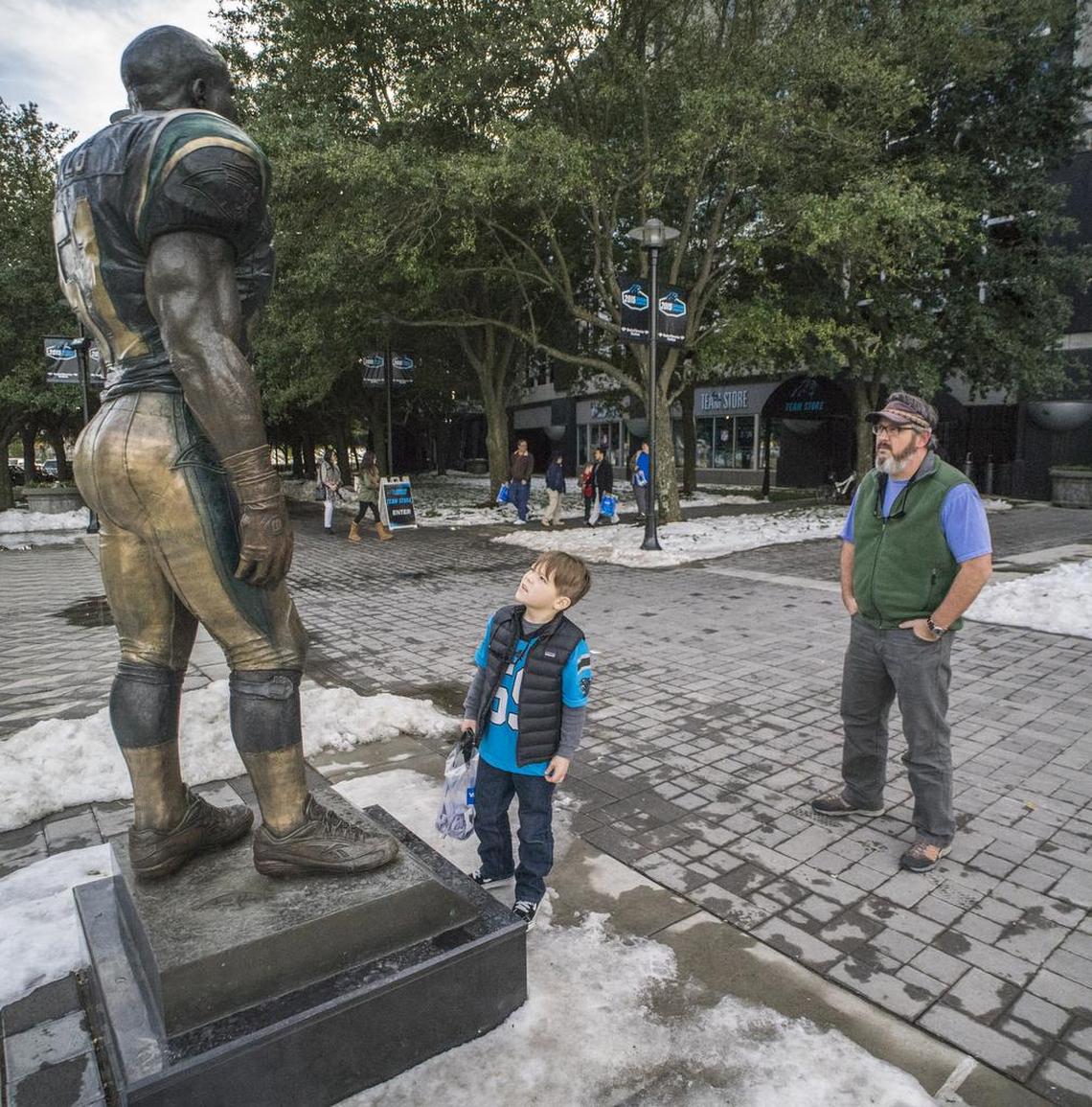 Podge Clark of Charlotte gives his son a lesson in the meaning of “Keep Pounding” in front of the Sam Mills statue in 2016.