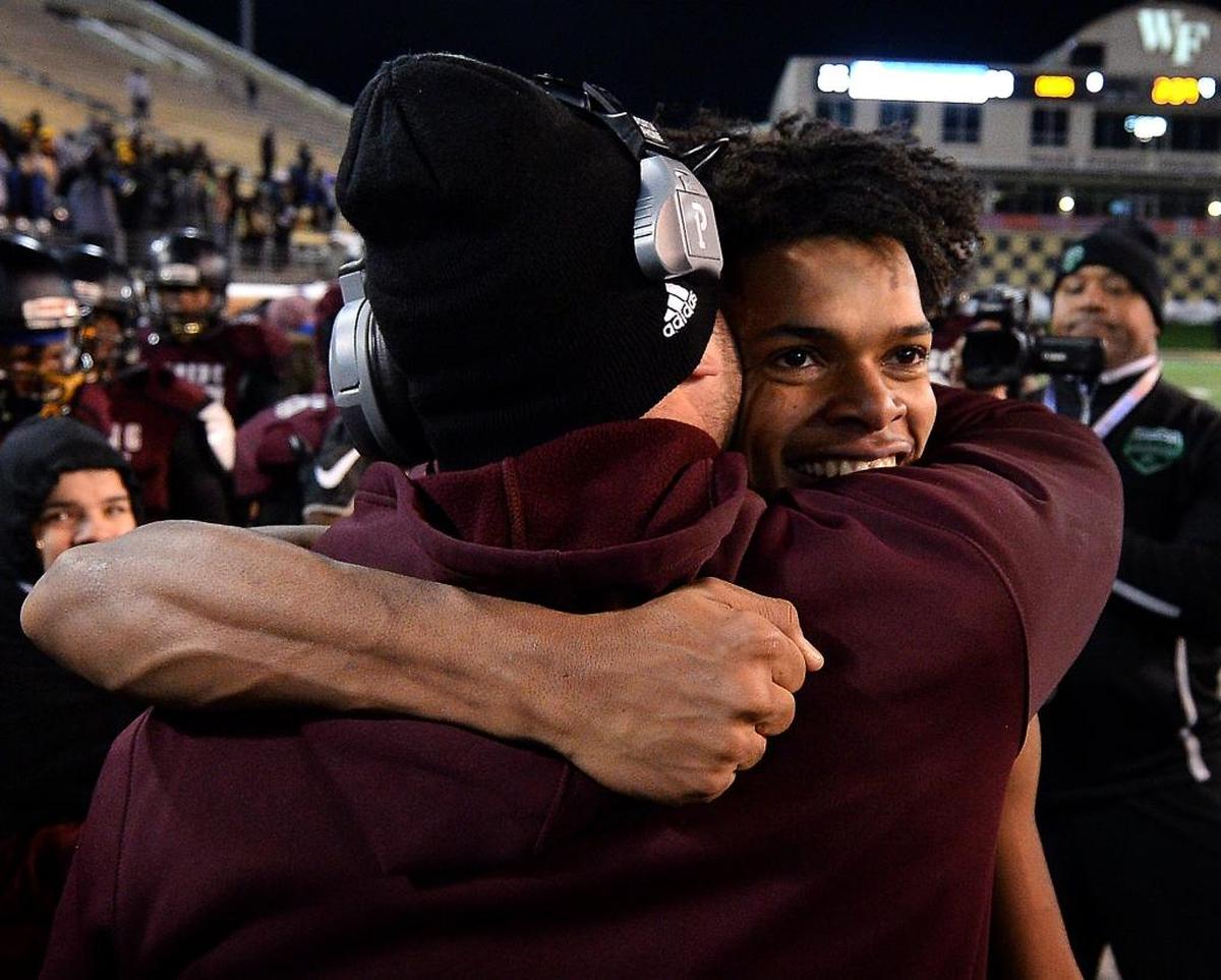 Harding University head coach Sam Greiner, left and quarterback Braheam Murphy, right, embrace along the team's sideline after Murphy ran for a 95-yard touchdown against Scotland County during fourth quarter action in the NCHSAA 4A State Championship game at BB&T Field in Winston-Salem, NC on Saturday, December 9, 2017. Harding defeated Scotland County 30-22.