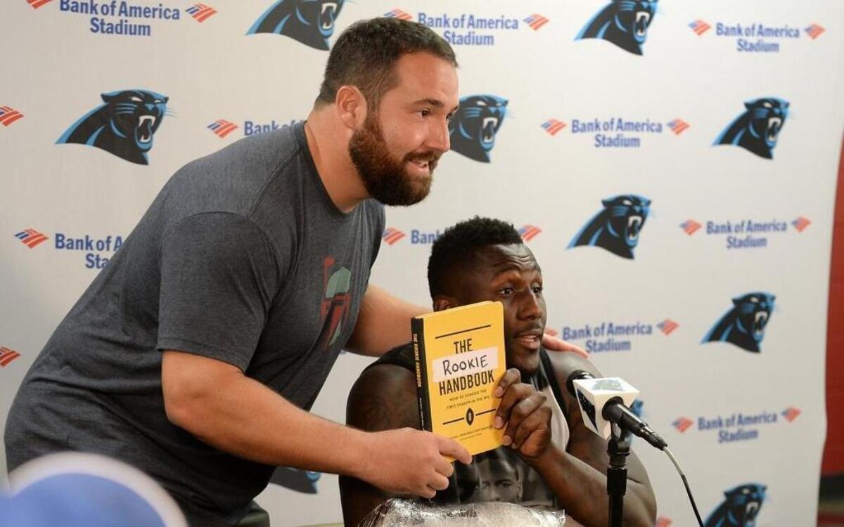 Carolina Panthers center Ryan Kalil, left, has teammate Thomas Davis, right, make a quick impromptu sales pitch for Kalil and former teammates Jordan Gross and Geoff Hangartner’s new book, “The Rookie Handbook,” during a press conference with the local media Sunday, July 31, 2016 following practice at Wofford College in Spartanburg, SC.
