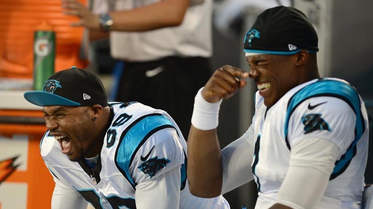 Steve Smith and Cam Newton laughing on the sidelines during a game.
