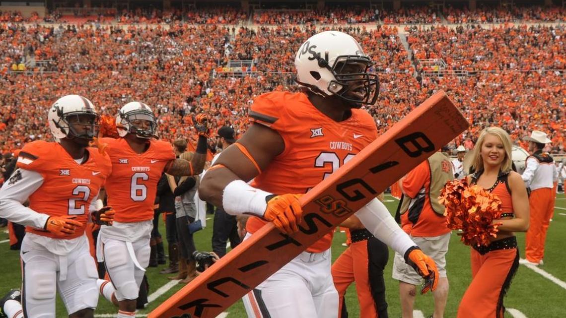 Oklahoma State defensive end Emmanuel Ogbah (38) carries the team’s “Big Stick” onto the field at the start of a game against Kansas in Stillwater, Okla. Ogbah led the Big 12 in sacks and is among the players the Carolina Panthers could consider with the 30th pick in the NFL draft.