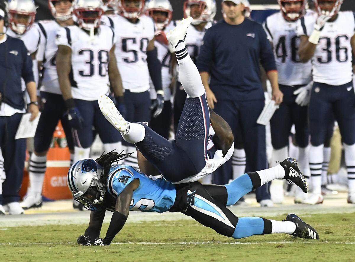 Carolina Panthers cornerback Donte Jackson (26) upends New England Patriots running back James White (28) in the first half at Bank of America Stadium in Charlotte, N.C., on Friday, Aug. 24, 2018. (David T. Foster III/Charlotte Observer/TNS)