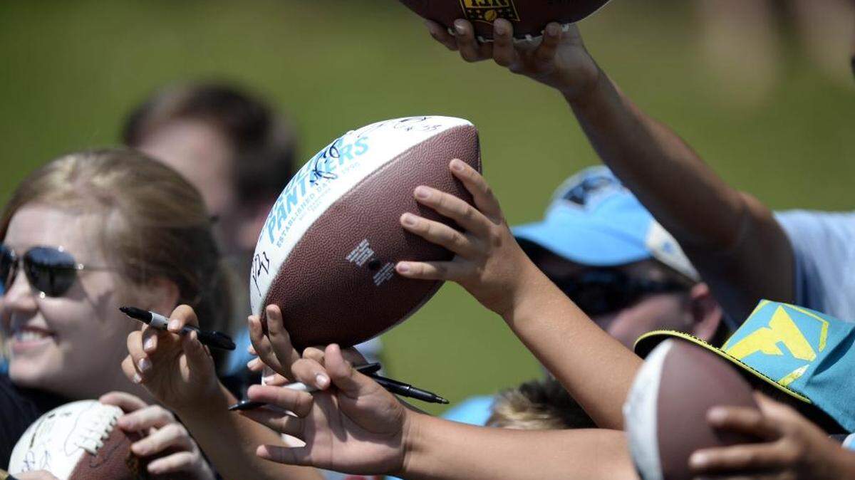 
Carolina Panthers fans holds up footballs hoping to get an autograph after morning practice at Wofford College in Spartanburg on Wednesday.
