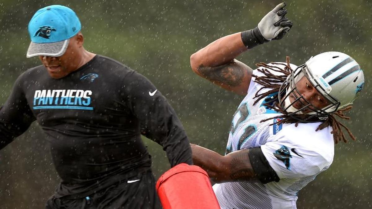 Carolina Panthers defensive end Ryan Delaire (right) races around defensive line coach Eric Washington during practice on Saturday. Delaire says he played much of last season with a shoulder injury that required surgery.