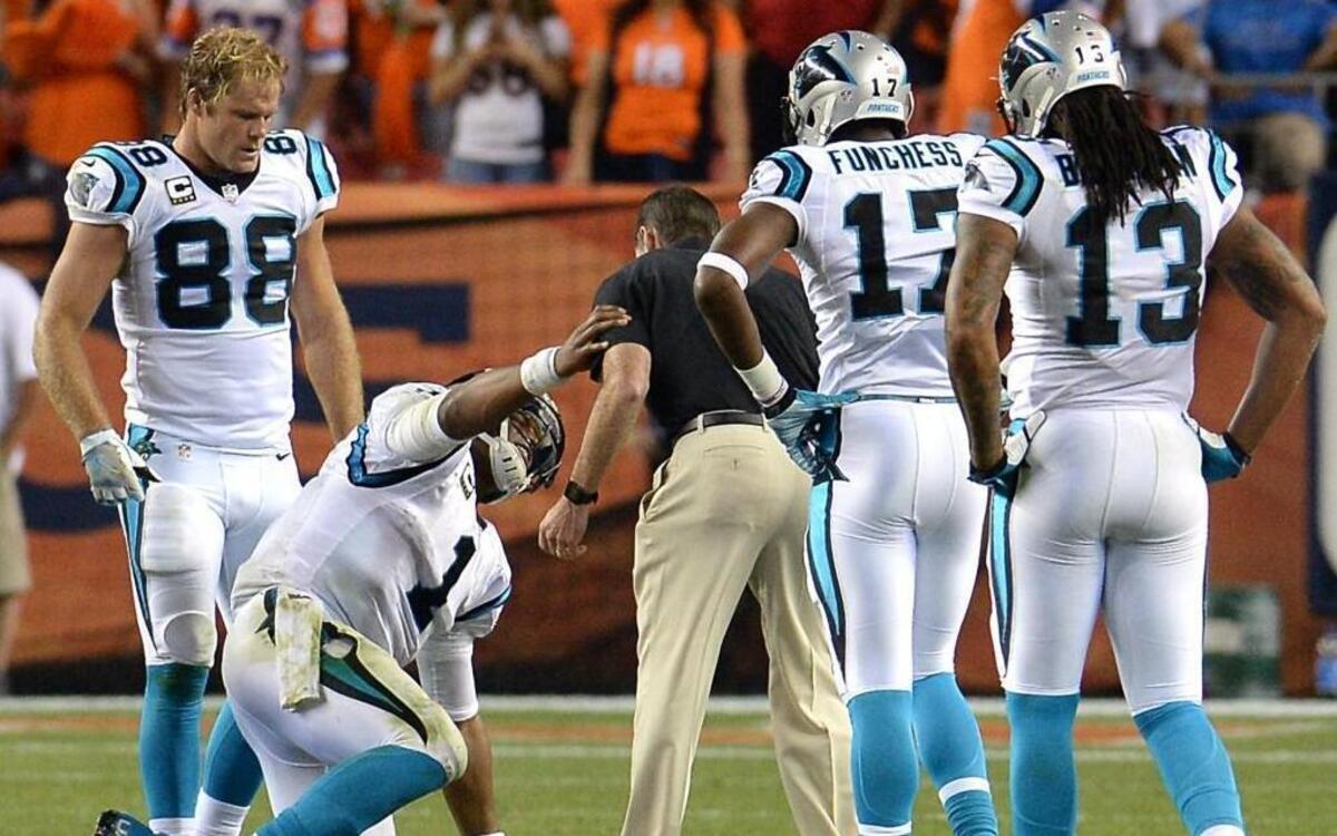 Carolina Panthers tight end Greg Olsen, from left, watches as quarterback Cam Newton steadies himself on head athletic trainer Ryan Vermillion's left arm as he slowly gets to his knees during the fourth quarter of Thursday’s 21-20 loss at Denver.