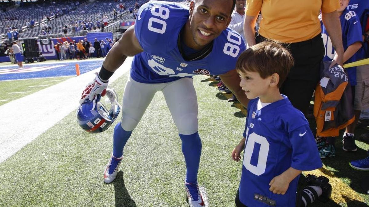 New York Giants wide receiver Victor Cruz (80) poses for a photo with a young fan before an NFL football game against the Arizona Cardinals Sunday, Sept. 14, 2014, in East Rutherford, N.J. (AP Photo/Kathy Willens)