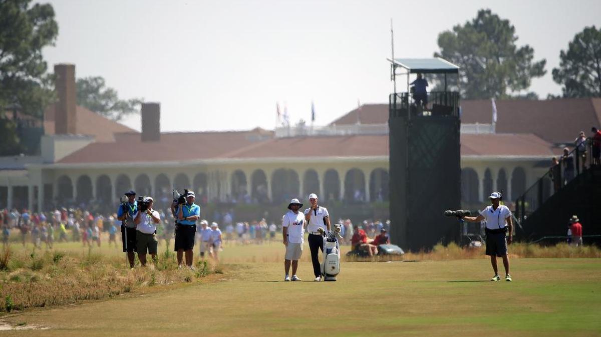 
With the Pinehurst clubhouse behind them, Martin Kaymer, right center, and his caddie Craig Connelly ponder a club selection on the second hole during the final round of the U.S. Open at Pinehurst No. 2 on June 15, 2014.
