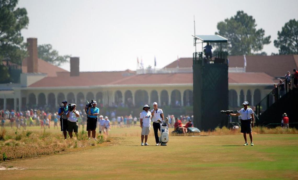 With the Pinehurst clubhouse behind them, Martin Kaymer, right center, and his caddie Craig Connelly ponder a club selection on the second hole during the final round of the U.S. Open at Pinehurst No. 2 on Sunday, June 15, 2014.