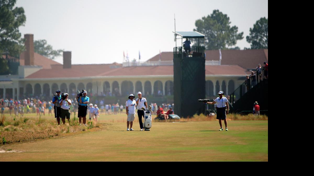 
With the Pinehurst clubhouse behind them, Martin Kaymer, right center, and his caddie Craig Connelly ponder a club selection on the second hole during the final round of the U.S. Open at Pinehurst No. 2 on Sunday, June 15, 2014.
