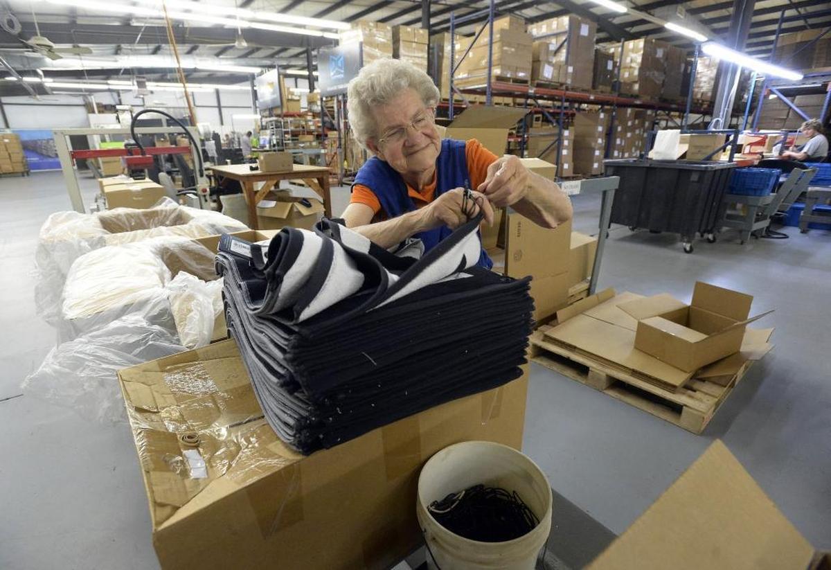 Doris Deese adds clasps to towels by hand while working at Devant Towels in Monroe on Wednesday. Everyone in the company affectionately calls her “Grandma.” The company has produced a selection of towels for the upcoming PGA Championship in Charlotte.