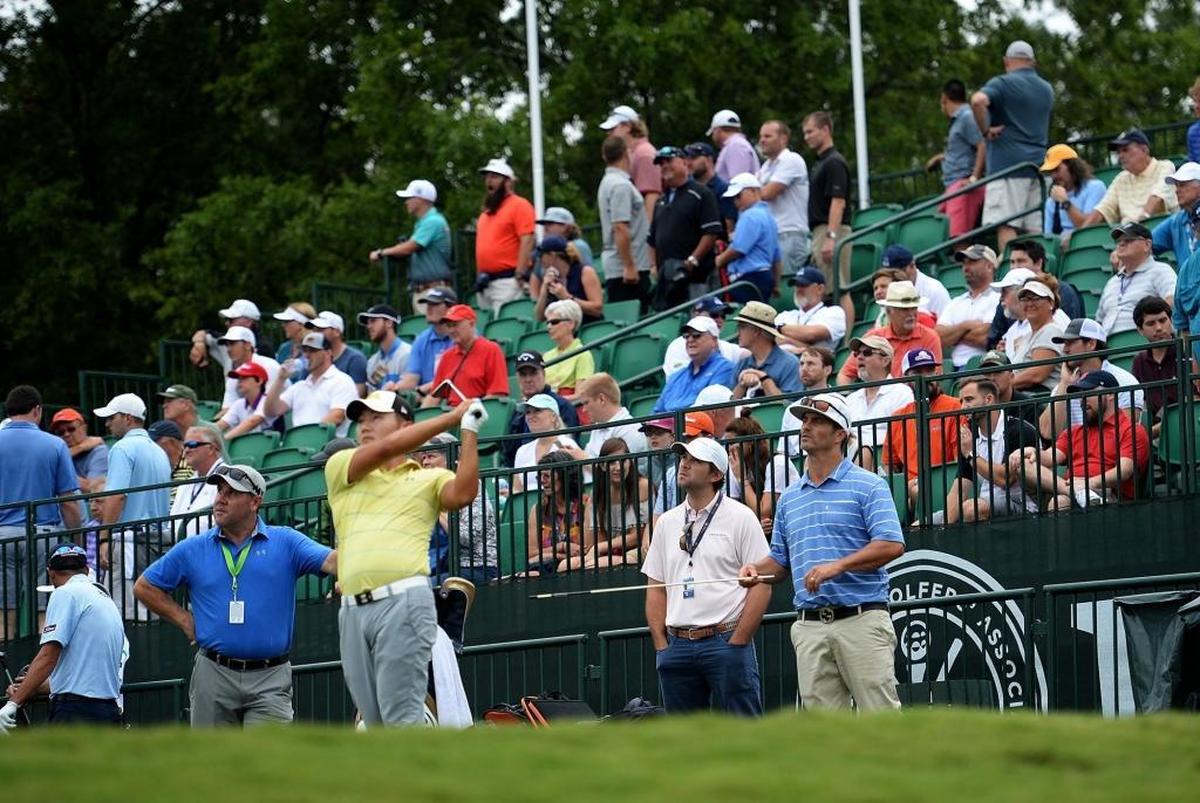 Under the watchful eyes of fans, golfer Sung Sang drives the ball on the practice range Monday.
