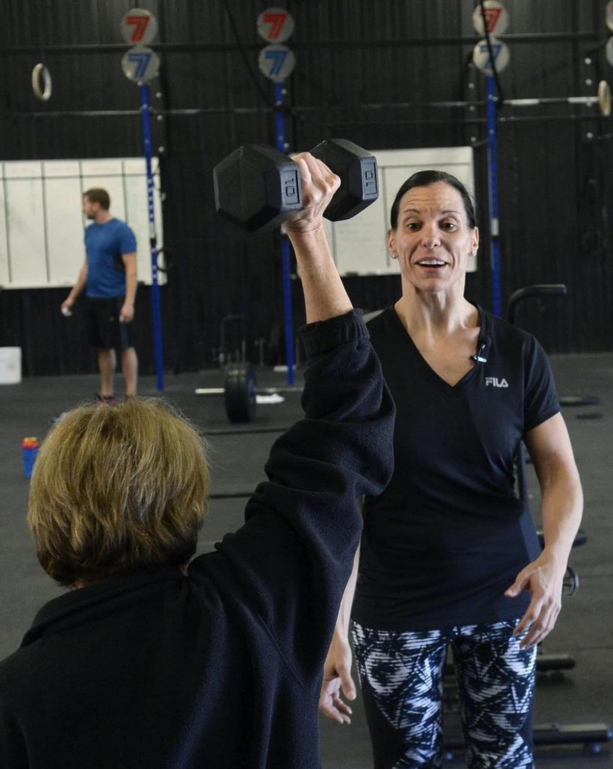 Brenda Keisler hoists at 10-pound barbell under the watchful eye of trainer Amanda Kloo, who is a favorite to win an international Crossfit competition at the end of January.