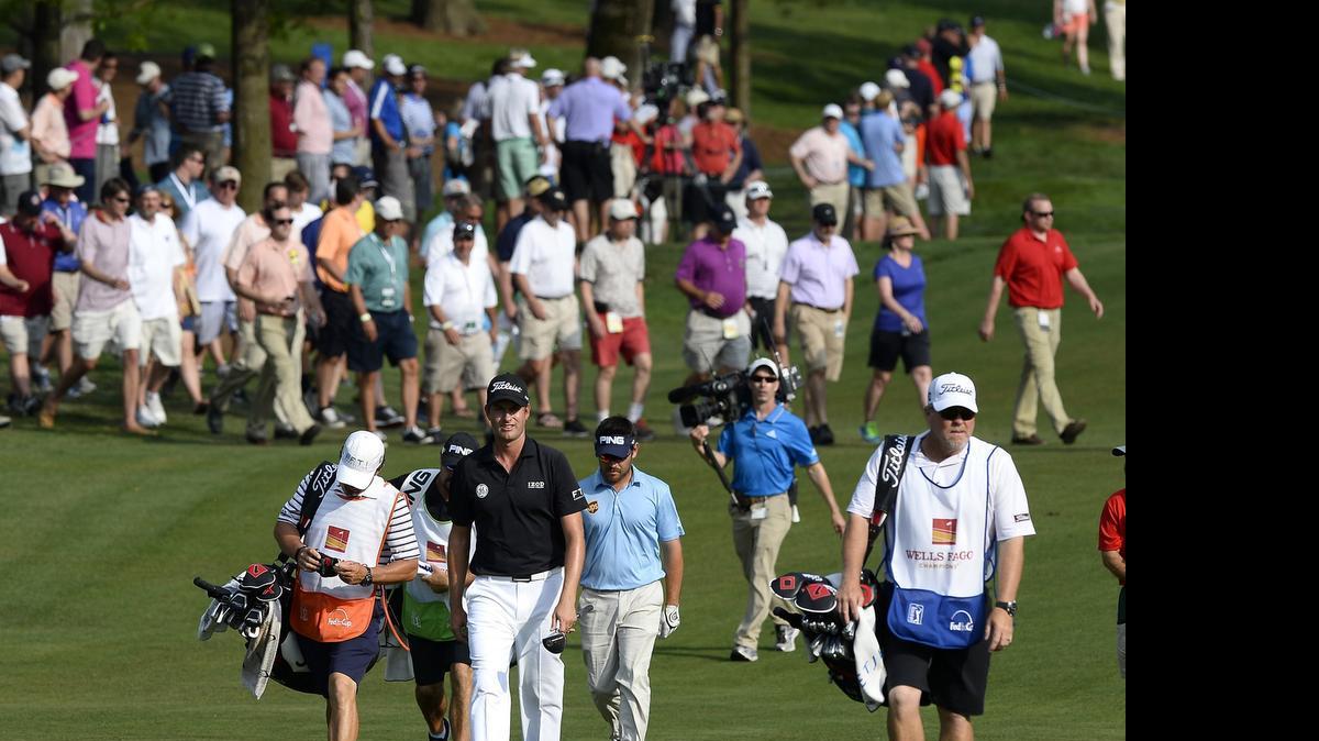 
Webb Simpson, center, walks up the 18th fairway during the second round of the Wells Fargo Championship at Quail Hollow Club.

