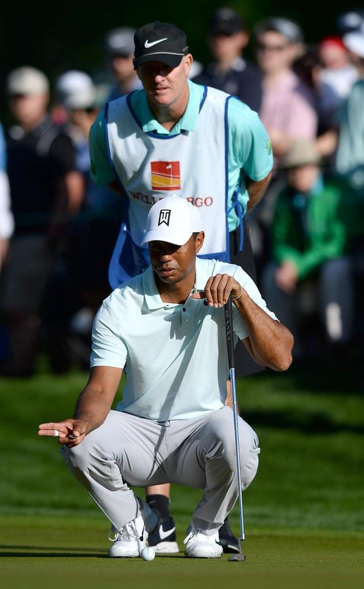 Tiger Woods and caddie Joe LaCava try to line up a putt on the 12th hole during the second round of the Wells Fargo Championship at Quail Hollow Club.