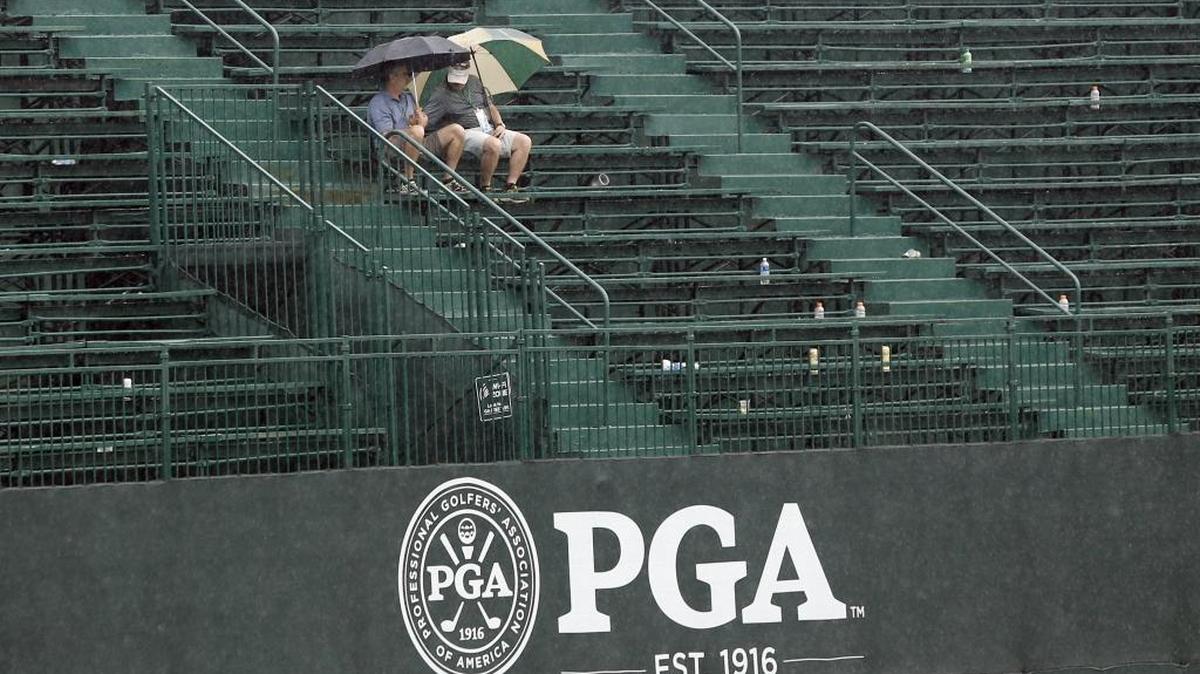 Two fans sit only in the grandstand on the 18th green during a weather delay in the third round of the PGA Championship golf tournament at Baltusrol Golf Club in Springfield, N.J., Saturday, July 30, 2016.