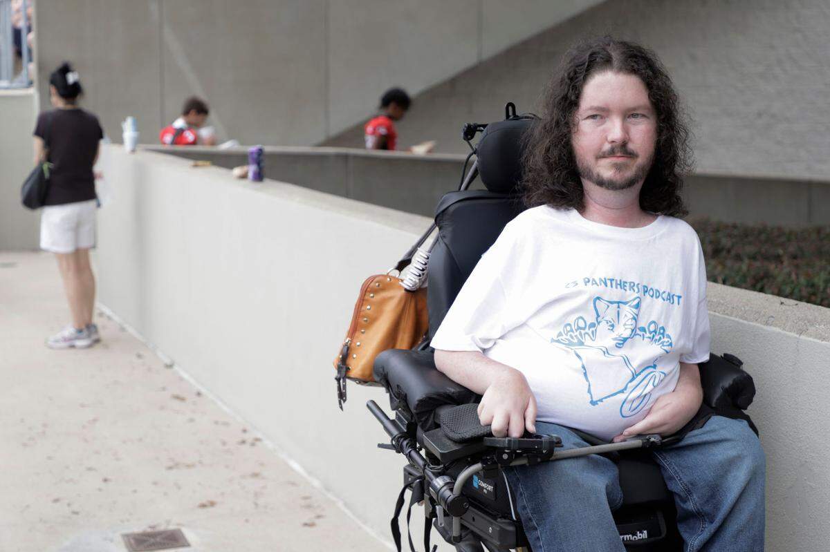Cody Lachney watches a Carolina Panthers training camp practice at Gibbs Stadium. Lachney has spinal muscular atrophy and is a host on the C3 Panthers podcast. (Sean McInnis / Charlotte Observer)