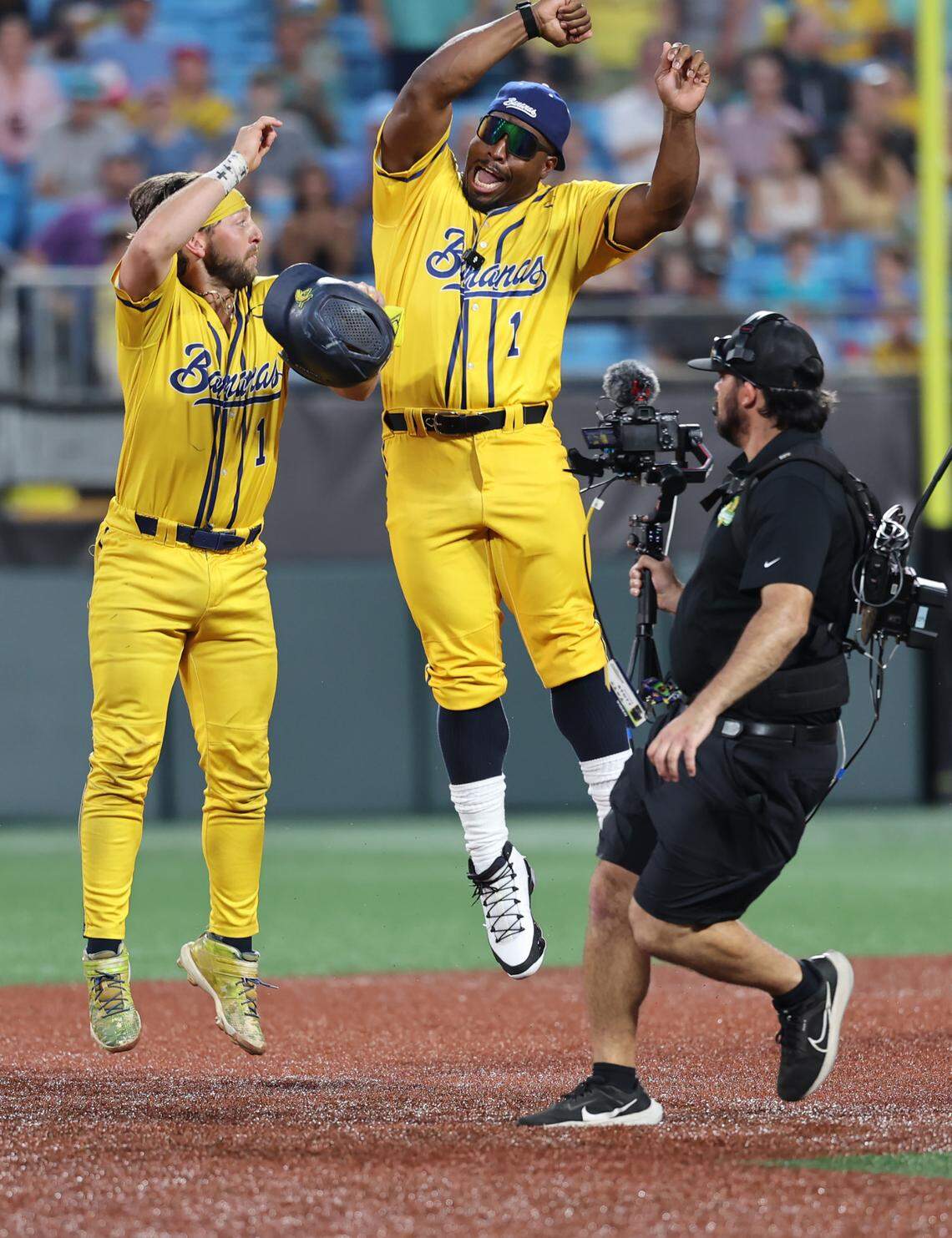 Bananas’ Bill Leroy, left, and Carolina Panthers’ Jonathan Stewart leap in the air Friday, June 6, 2025 at Bank of America Stadium in Charlotte.