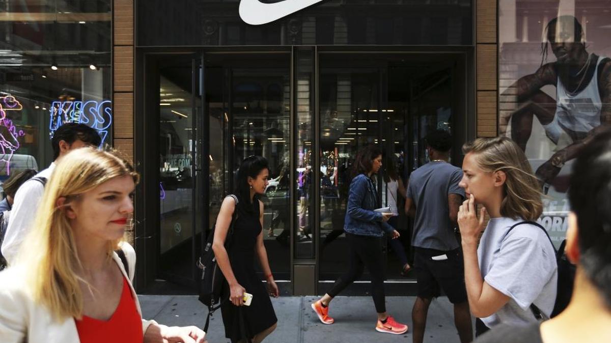 Pedestrians walk by the Nike Soho store, Thursday, June 15, 2017, in the SoHo neighborhood of New York. Nike said Thursday that it plans to sell more shoes directly to customers online as part of a restructuring in which it plans to cut about 1,400 jobs. It will also reduce the number of sneaker and clothing styles it makes by a quarter and focus on hot sellers. (AP Photo/Michael Noble Jr.)