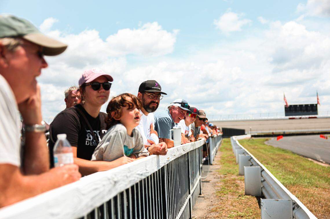 Fans lean over an infield fence as cars roar Rockingham Speedway back to life on Saturday, July 13, 2024, at an open house for the North Carolina track that was once a staple in the NASCAR Cup Series.