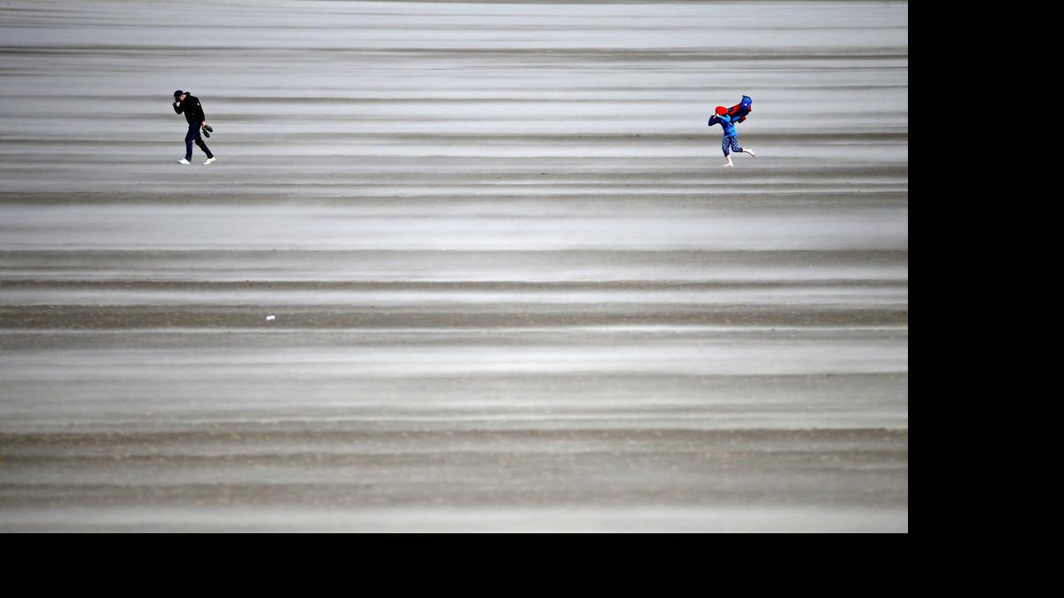 
People walk on a windswept beach near the course as high winds suspend play during the second round of the British Open Golf Championship at the Old Course, St. Andrews, Scotland, Saturday, July 18, 2015. (AP Photo/Jon Super)
