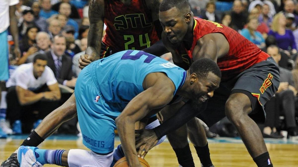 Charlotte Hornets' Kemba Walker (15) works to keep control of the ball as Atlanta Hawks' Paul Millsap (4) and Kent Bazemore (24) defend in the second half at Time Warner Cable Arena on Sunday. Atlanta won, 94-92.