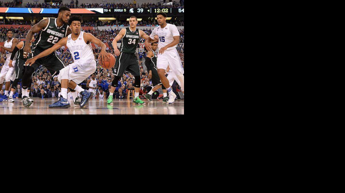 
Duke’s Quinn Cook (2) grabs a loose ball from Michigan State’sBranden Dawson (22) during the NCAA national championship semifinal game on Saturday. 
