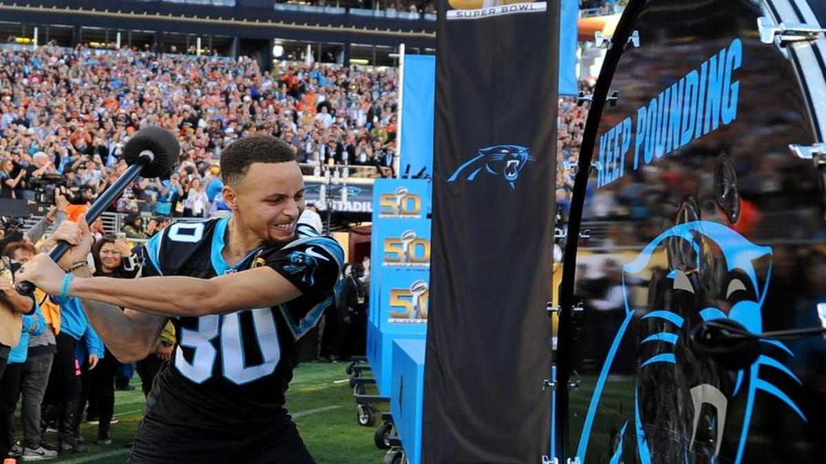 NBA star Stephen Curry, shown hitting the “Keep Pounding” drum before February’s Super Bowl, plans to come to the Oakland-Carolina game Sunday. Curry says he believes Panthers quarterback Cam Newton will come to one of his Golden State games this week.