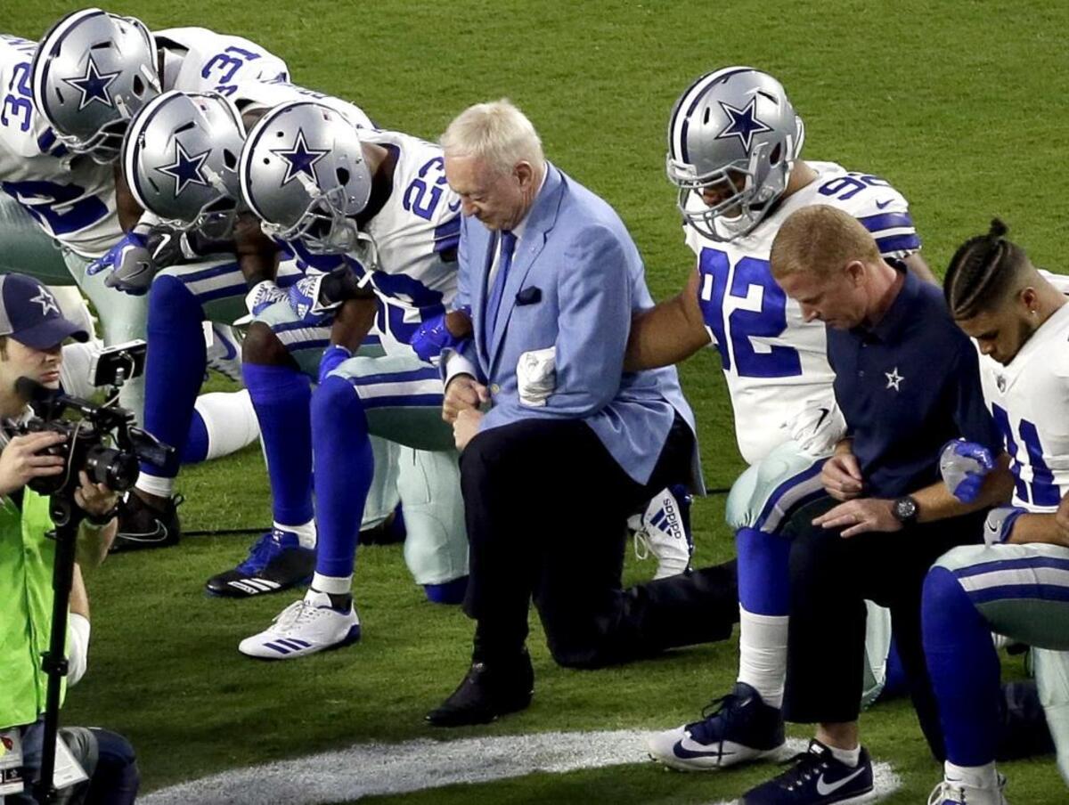 Dallas owner Jerry Jones, center, took a knee with his players prior to the playing of the national anthem Monday night in Glendale, Ariz. What began more than a year ago with a lone NFL quarterback protesting police brutality against minorities by kneeling silently during the national anthem before games has grown into a roar with hundreds of players sitting, kneeling, locking arms or remaining in locker rooms, their reasons for demonstrating as varied as their methods.