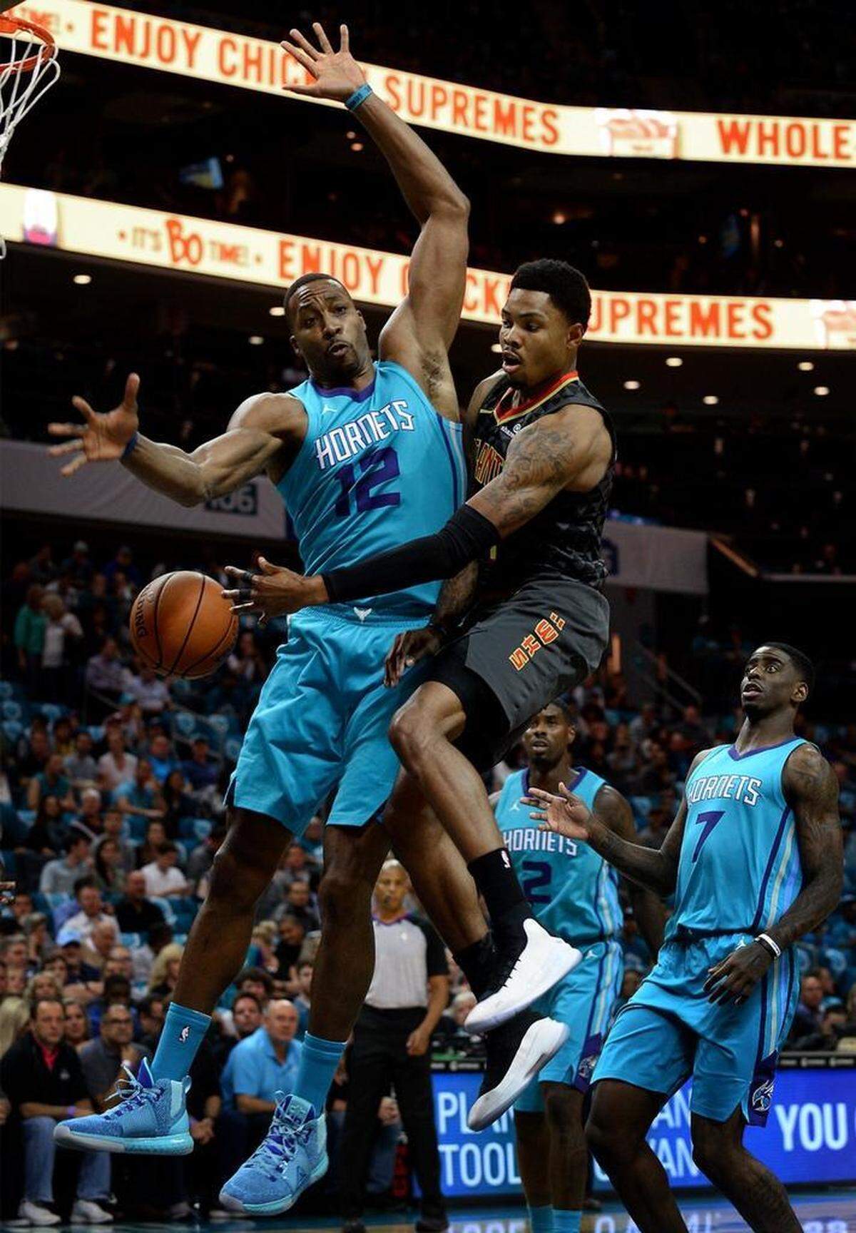 Charlotte Hornets center Dwight Howard, left, applies defensive pressure as Atlanta Hawks guard Kent Bazemore, right, passes the ball to a teammate during first-quarter action on Friday.
